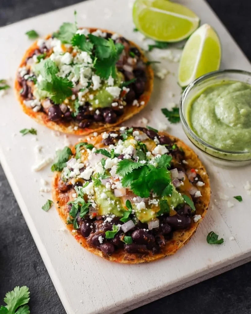 Plate of crispy black bean tostadas topped with fresh vegetables and avocado