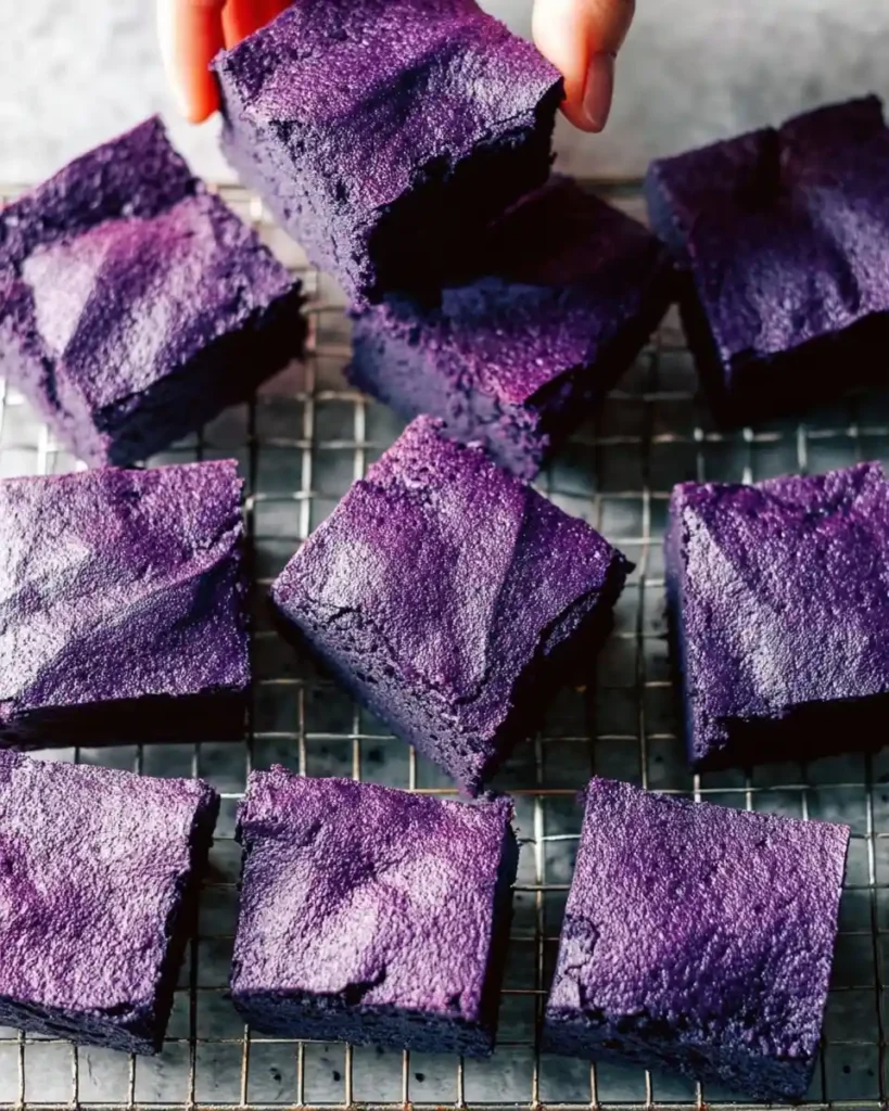 A hand picks up a vibrant piece of {{ $('Fetch Recipe Data').first().json["Main Keyword"] }} from a wire cooling rack.