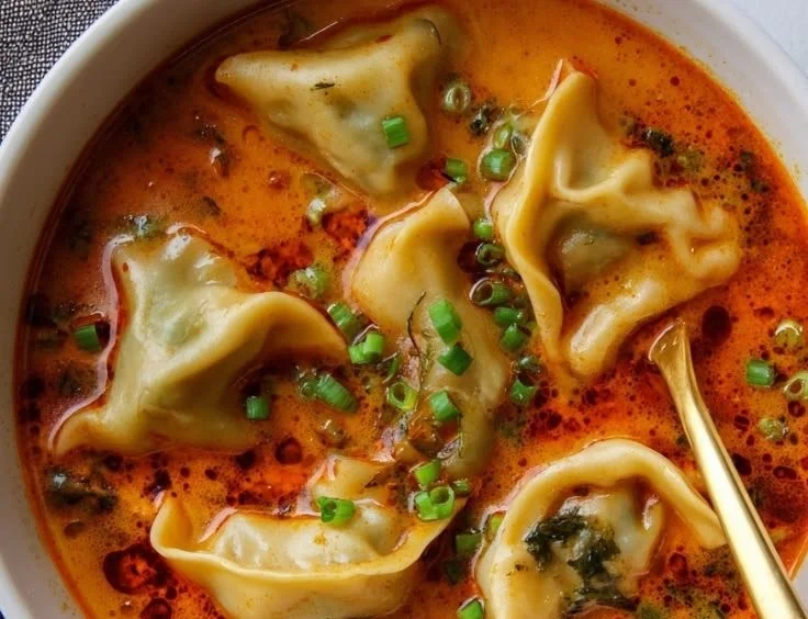 Bowl of creamy Coconut Curry Soup with herbs and spices garnished on top.