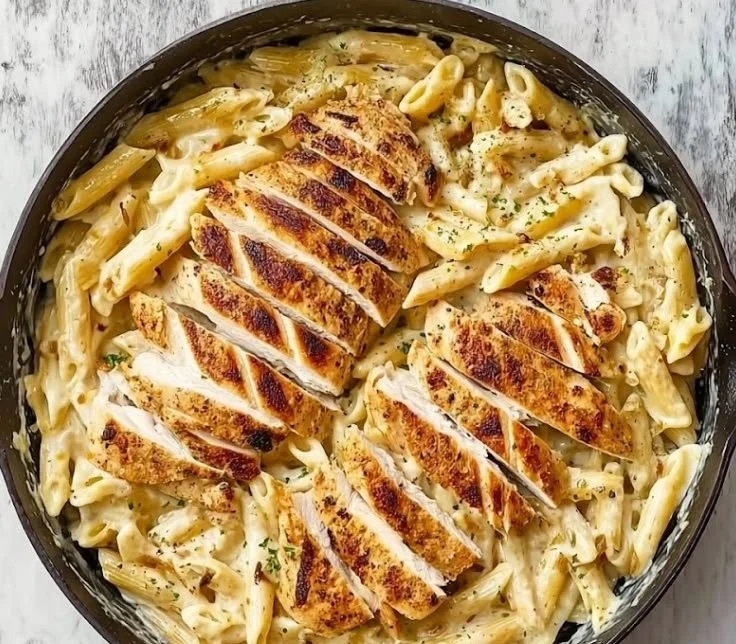 Creamy garlic parmesan chicken pasta dish served in a bowl with herbs.